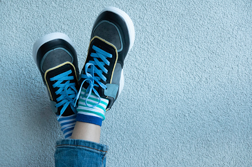 Kid wearing different pair of socks. Legs in mismatched socks on gray background. Odd Socks day, Anti-Bullying Week. Down syndrome awareness concept