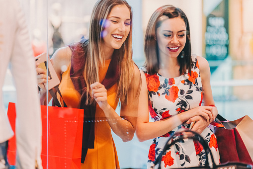 Happy women in the shopping mall looking at the shop window