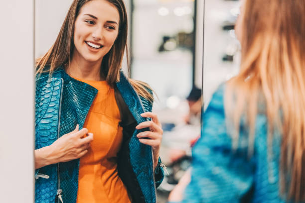Young woman in the shopping mall enjoying a leather jacket Happy women in the clothing store fitting room stock pictures, royalty-free photos & images