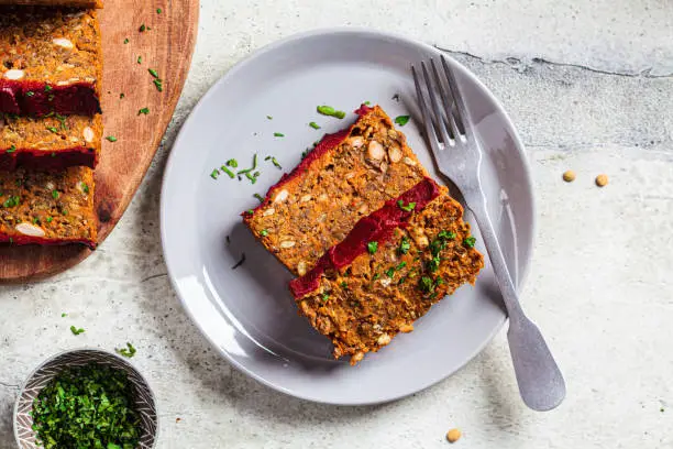 Lentil vegan meatloaf slices on a gray plate, top view. Christmas plant-based recipe.