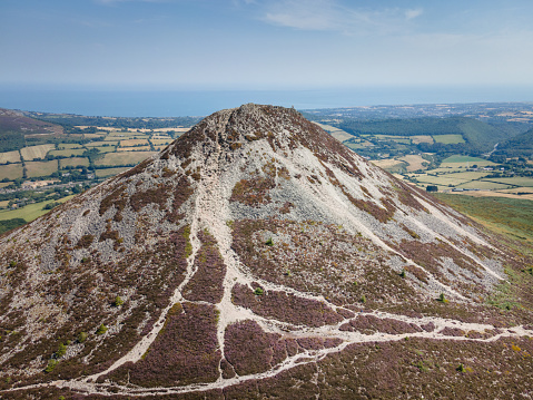 Drone aerial view of Sugarloaf mountain, County Wicklow, Ireland, on a hot sunny summer day with blues skies and green fields in the distance. The mountain is very popular with hikers and walkers and is a tourist attraction, you can see the village of Greystones in the background and the Irish sea