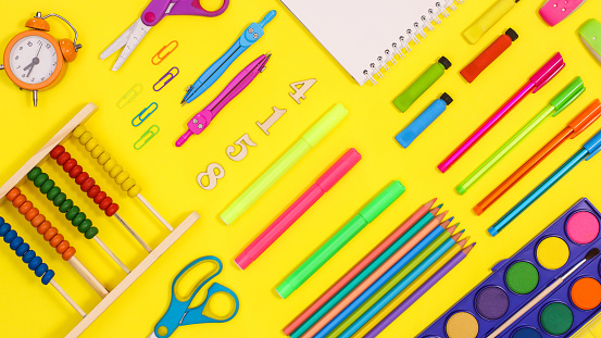 Back to school pattern made with school stationery on vibrant yellow background. Flat lay
