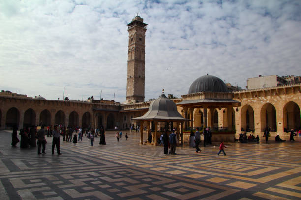 Young Muslim woman standing in front of a mosque minaret in Mardin