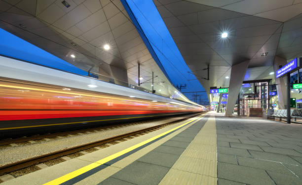 istock High speed train in motion on the railway station at night. Moving red modern intercity passenger train, railway platform, architecture, city lights. Modern train station in Vienna, Austria. Railroad 1415031454