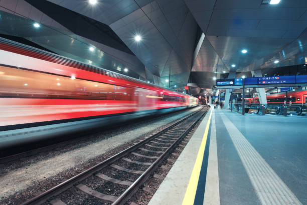 istock High speed train in motion on the railway station at night. Moving red modern intercity passenger train, railway platform, architecture, city lights. Modern train station in Vienna, Austria. Railroad 1415031467