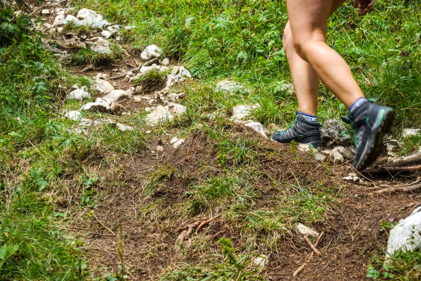 Hiking young woman trekker with trekking boots walking outdoors on a trail in the Italian mountains