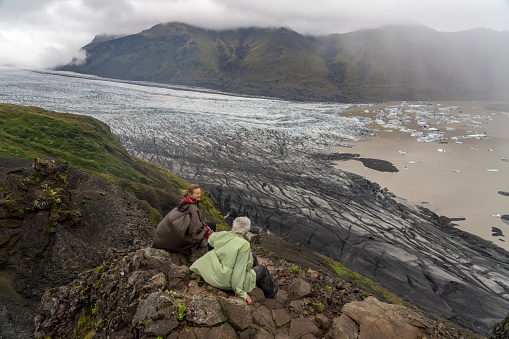 Mature couple sitting high up over the Skaftafell Glacier in Vatnajokull National Park, South Iceland