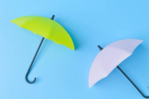 istock Green and white umbrella isolated on a blue background 1415040752