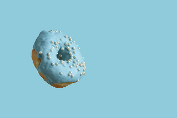 istock Donuts covered with pale blue icing and sprinkled with pearl sugar beads on a light blue background. Closeup 1415043281