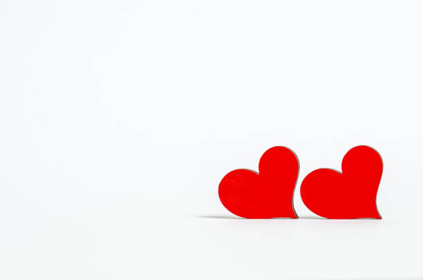 Two small handmade red wooden hearts on red background Valentines day card
