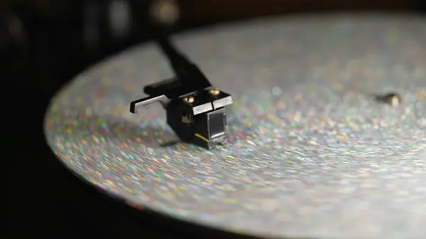 Photo of Retro-styled spinning silver record vinyl player. Close up glitter surface. Rotating vintage phonograph. Beautiful picture. Copy space,