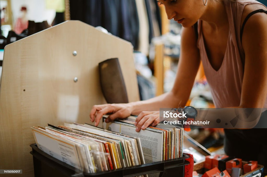 browsing music at the vinyl records shop Woman is browsing through the vinyl records in the vintage music shop in Berlin. Record - Analog Audio Stock Photo