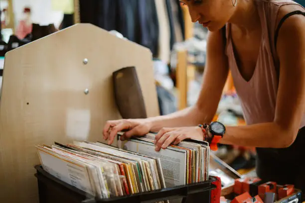 Woman is browsing through the vinyl records in the vintage music shop in Berlin.