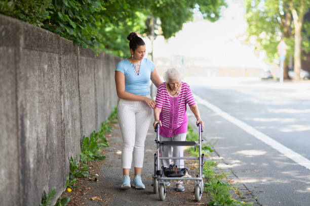 istock Young hispanic carer supporting senior woman in her nineties while walking supported by walker 1415050950