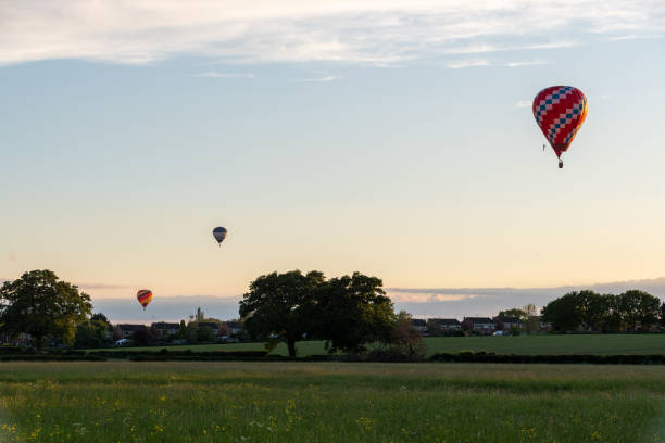 istock Distant hot air balloons float across a field 1415053059