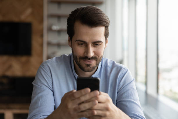 istock Happy millennial man using app on smartphone, making telephone call 1415053228