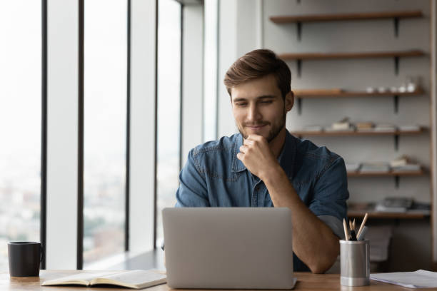 istock Happy satisfied millennial man using laptop at office workplace 1415053346