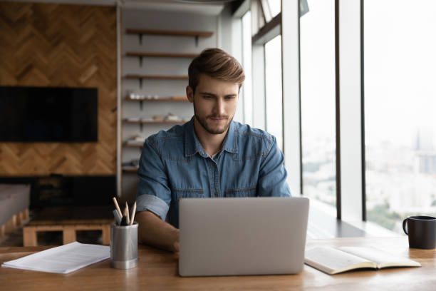 istock Serious distance employee working from home, using laptop 1415053352