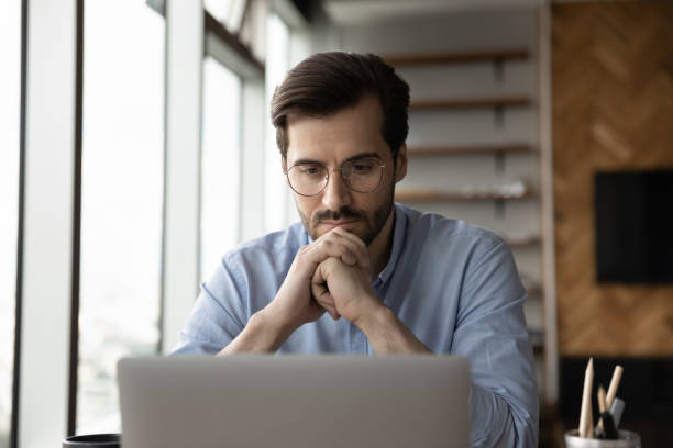 istock Thoughtful focused business man in glasses working at laptop computer 1415053463
