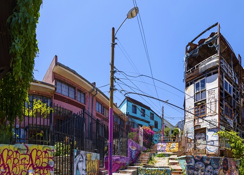 Valparaíso, Chile, December 11, 2018: View of a staircase in this city of poets, bohemians, adventurers with many graffiti and paintings on the walls on a sunny day. The streets lead mostly downhill or uphill.