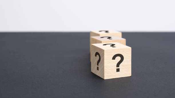istock staggered row of three wooden blocks with question marks black on black table, copy space 1415054438