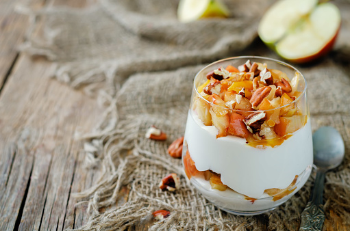 Caramelized apple pecan greek yogurt parfait in a glass. toning. selective focus