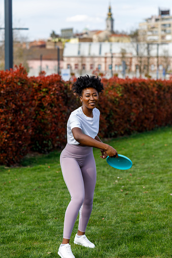 Beautiful African Woman is Throwing a Frisbee and Enjoying in Summer Day with Friends.