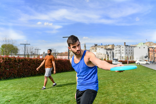 Handsome Man is Throwing a Frisbee and Enjoying in Summer Day with Friends.