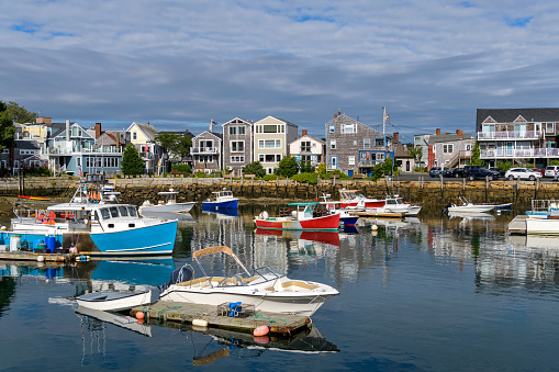A sunny Autumn morning view of colorful fishing boats docking in the peaceful inner harbor of Rockport, a small seaside resort town at tip of Cape Ann, near Boston, Massachusetts, USA.