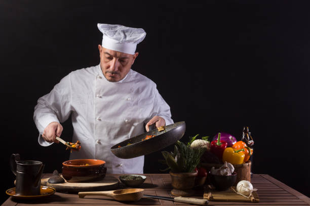 istock Male chef in white uniform preparing food plate with vegetables 1415055619