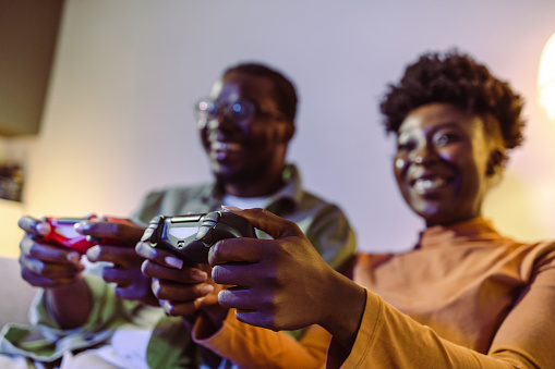 Low angle view of a cheerful young couple playing video games and having fun at home. Leisure game night at home