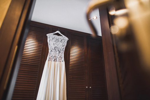 Wedding dress hanging on a wooden wardrobe.