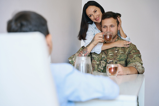 Military man in marching clothes with his charming wife and teenage son over morning tea in a pleasant environment