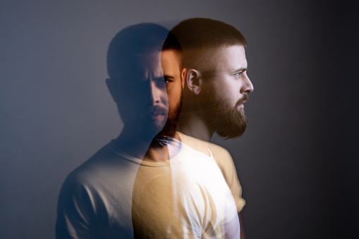 Double exposure crative side view profile and portrait of artistic bearded model man in white t-shirt looking at camera with calm serious face. special blurred beauty effect. indoor studio shot.