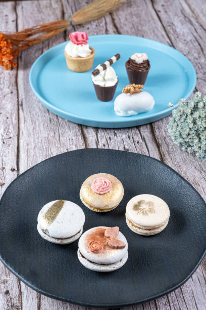 istock Macarons decorated with edible ink and fondant. In the background assorted sweets with whipped cream and nuts. 1415065927