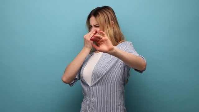 Woman standing pinching her nose with fingers to hold breath, disgusted by stinky intolerable smell.