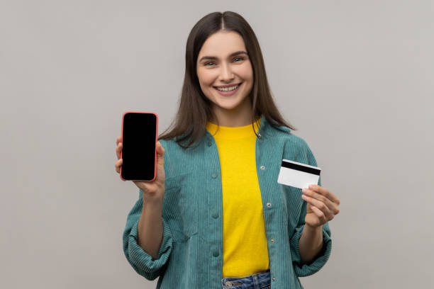 Bank customer being happy of good mobile banking. Smiling woman holding credit card and cell phone. stock photo