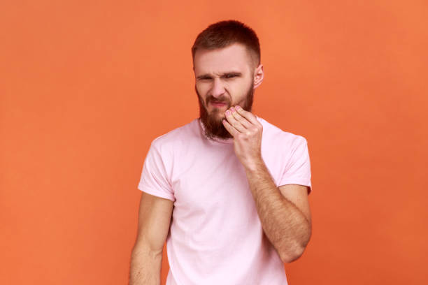 istock Man touching his cheek and grimacing from terrible toothache, sensitive teeth. 1415066967