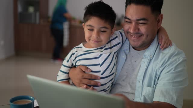 Father using laptop working with son at home