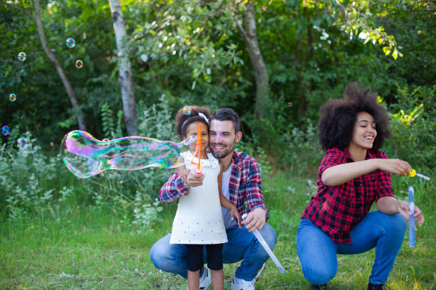 istock Happy family playing soap bubbles in park 1415071463