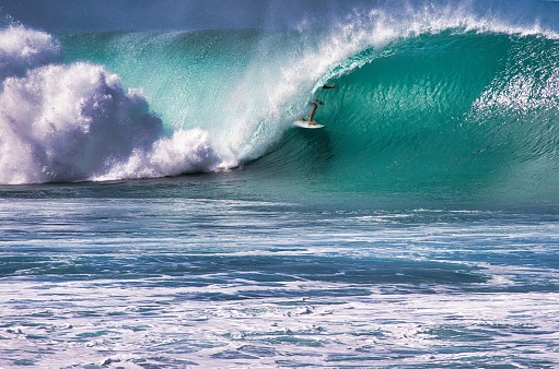 Surfer riding inside the tube of a big wave on Maui.