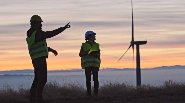 Wind energy engineers working in wind farm at dusk. Renewable Energy Systems. Carbon neutrality and sustainable energy. stock photo