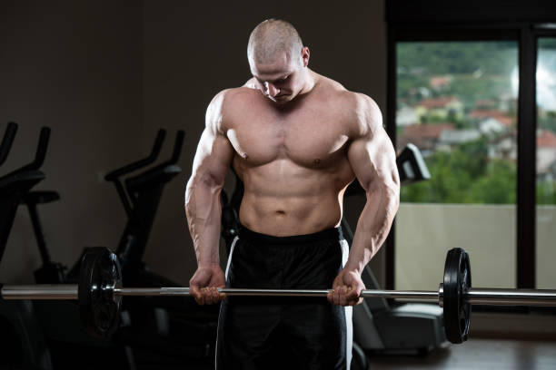 homme dans la salle de sport exercice biceps avec barre d'haltères - barre dhaltères photos et images de collection