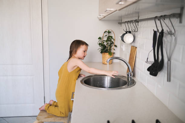 istock Funny baby washes his hands in bright real kitchen 1415079163