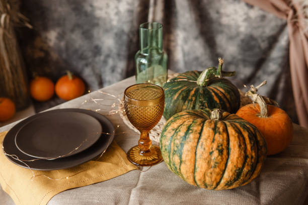istock Autumn interior: a table covered with dishes, pumpkins, a relaxed composition of Japanese pampas grass. Interior in the photo Studio. Close - up of a decorated autumn table. 1415079173