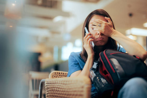 unhappy woman talking on the phone waiting in an airport - waiting telephone on the phone anxiety imagens e fotografias de stock