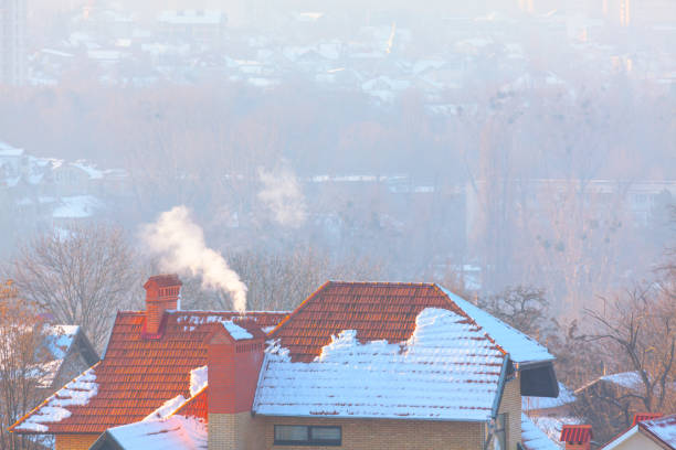 istock Chimney with smoke and tiled roof 1415082511