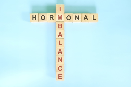 Hormonal imbalance concept. Wooden blocks crossword puzzle flat lay in blue background.
