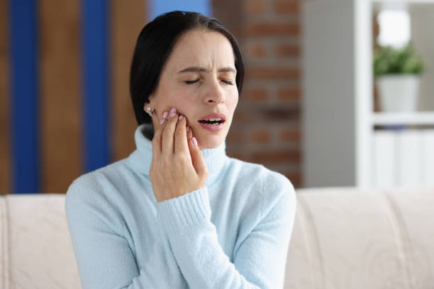 istock Young woman with acute toothache on couch 1415098464