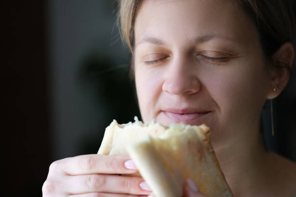 istock Happy woman with closed eyes holding white bread 1415098540